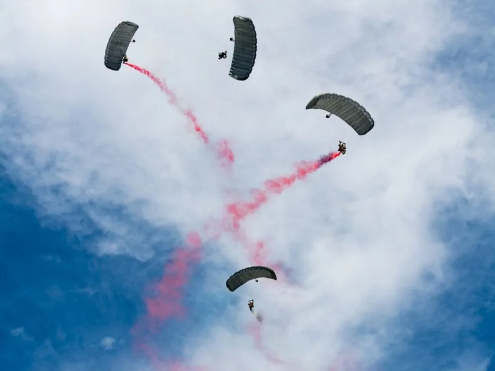 Man sieht Fallschirmspringer, die mit Farbe eine Show vorführen.